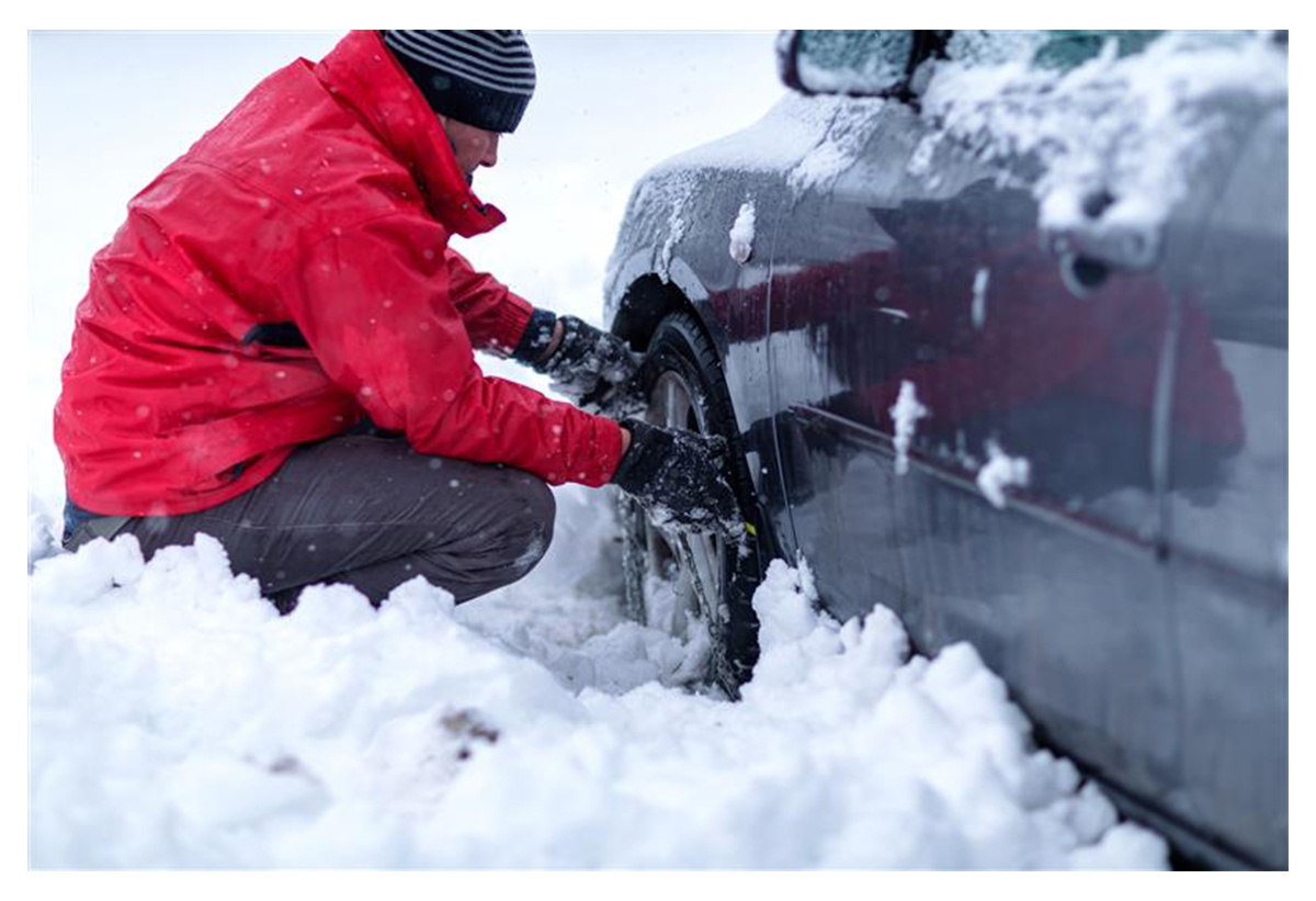 Απεικονίζει ένα αυτοκίνητο με φορεμένες τις χιονοκουβέρτες σε ένα δρόμο με χιόνια